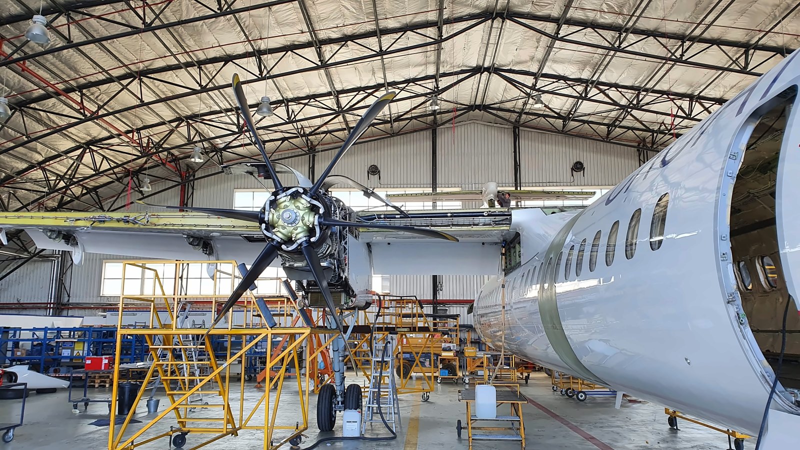 Turboprop aircraft in the hangar with engine cowlings open during inspection
